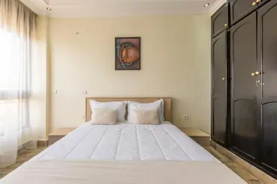 a bedroom with a large white bed with a picture on the wall at Appartement Raffiné au Centre in Marrakech