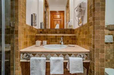 a bathroom with a sink and a mirror and towels at Family Stay aux jardins de la palmeraie in Marrakech
