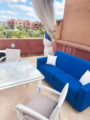 a blue couch and a table and chairs on a balcony at Appartement avec Solarium Privé au Vizir Résidence Prestigieuse avec Accès au Parc in Marrakech