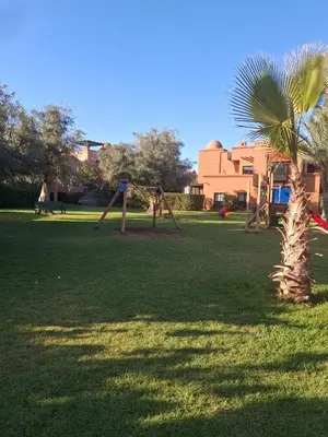 a park with a palm tree and a swing set at Havre de paix bohème avec rooftop privée in Marrakech
