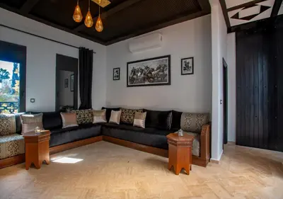 a living room with a black couch and tables at Riad Tamazgha in Marrakech