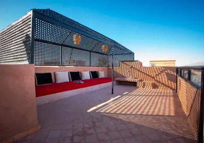 a rooftop patio with a red couch on a building at Riad Tamazgha in Marrakech