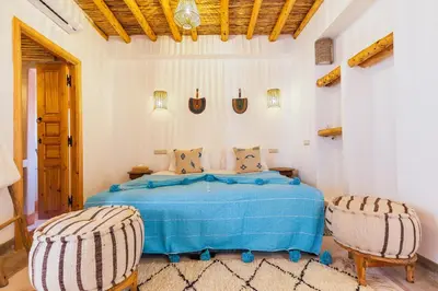 a bedroom with a blue bed with two chairs at Riad Mama in Marrakech