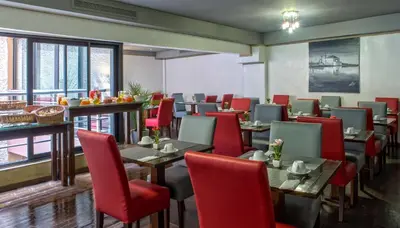 a dining room with tables and red chairs at Yaad City Hotel in Marrakech