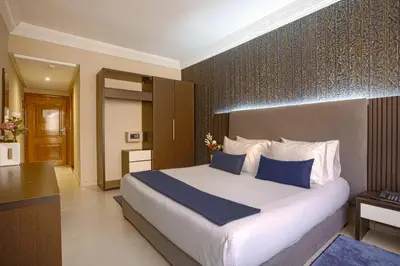 a bedroom with a large white bed with blue pillows at Yaad City Hotel in Marrakech