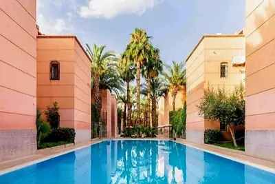 a large swimming pool in a building with palm trees at Riad yazuinaa in Marrakech
