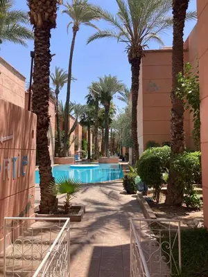 a resort with a swimming pool with palm trees at Riad Lalla Aicha -Piscine, 3 suites climatisées & terrasse in Marrakech