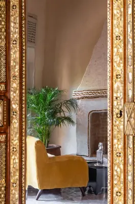 a living room with a yellow chair and a fireplace at Riad Dar Al Dall - This Time Tomorrow in Marrakech in Marrakech