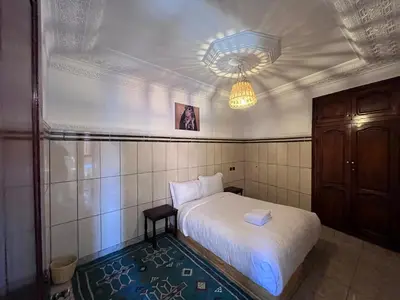 a small bedroom with a white bed and a chandelier at Riad Dar Zarbia in Marrakech