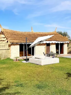 a house with an umbrella and a table and a couch at THE FARM LODGES & Private pool in Marrakech