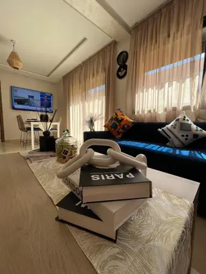 a living room with a couch and a pile of books at Charming Appartment in Gueliz in Marrakech