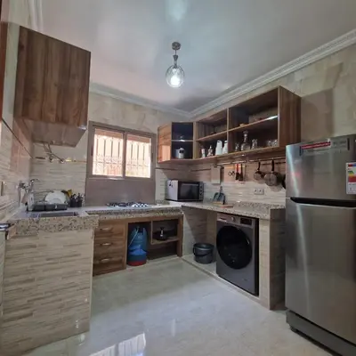a kitchen with wooden cabinets and a stainless steel refrigerator at Bel appartement de 2 chambres L in Marrakech