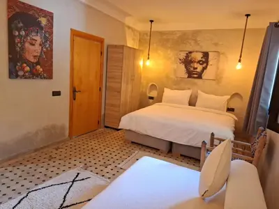 a bedroom with a bed and a chair in a room at Duplex Riad Abjaou in Marrakech