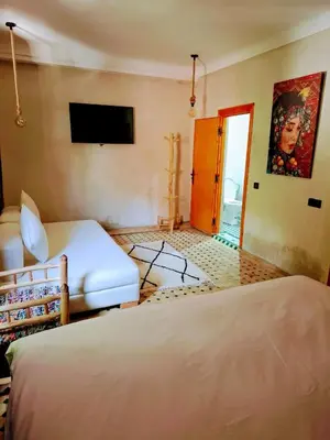 a hotel room with two beds and a television at Duplex Riad Abjaou in Marrakech