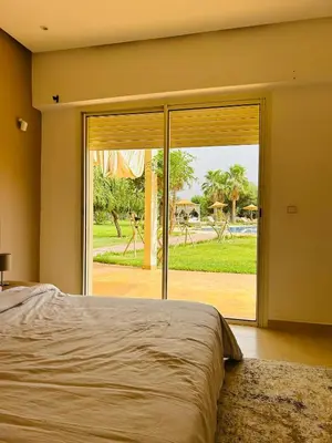 a bedroom with a bed and a large sliding glass door at Séjour idéal a Marrakech - Villa spacieuse tout confort in Marrakech