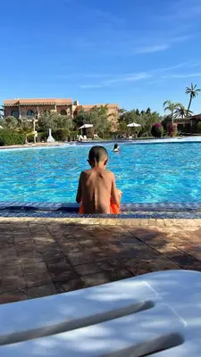 a man sitting in front of a swimming pool at Appartement Spacieux avec Piscine à la Palmeraie in Marrakech