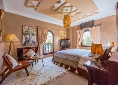 a bedroom with a bed and a tv and two windows at Villa Malika Silvana in Marrakech
