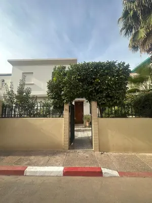a white house with a gate with a tree at Maison de ville avec piscine privée in Marrakech