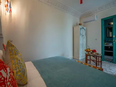 a bedroom with a bed and a side table at Riad dada Messouda spa in Marrakech