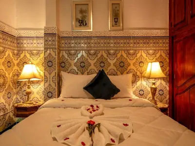 a bedroom with a bed with white sheets and flowers on it at Agréable Maison de vacances in Marrakech