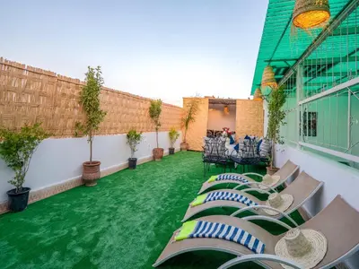 a patio with chaise lounges and chairs on a green lawn at Agréable Maison de vacances in Marrakech