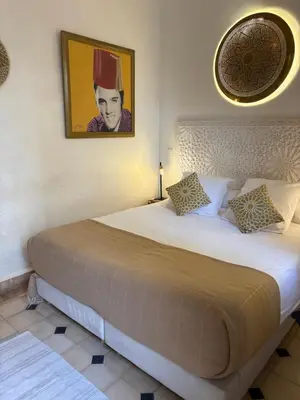 a bedroom with a large bed with a picture on the wall at Le riad de l'étoile ocre - COTG in Marrakech