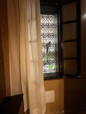 a window with a white curtain in a bathroom at Le riad de l'étoile ocre - COTG in Marrakech