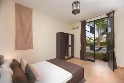 a bedroom with a bed and a view of a patio at Domaine Marradise in Marrakech