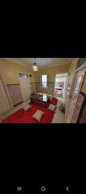 a large living room with a red rug and a room with windows at Riad Le Petit Cactus -Familial et Privatif- in Marrakech