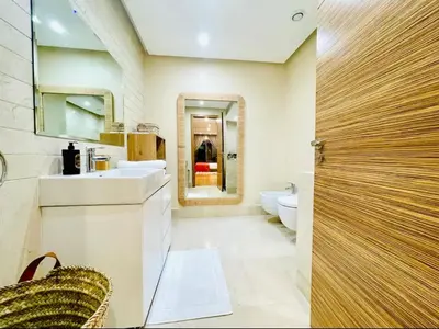 a bathroom with a sink and a toilet and a mirror at Appartement luxueux avec vue panoramique sur l’Atlas au centre de Marrakech in Marrakech
