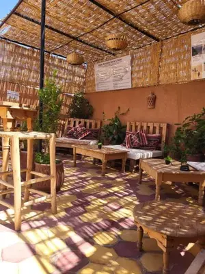 an outdoor patio with benches and tables and a roof at Medina Oasis Hostel in Marrakech
