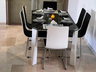 a black dining room table with white chairs at mini-villa situee dans une residence Prestigia à Marrakech, avec une vue sur la piscine et le golf une securite 24h sur 24 et une proximite ideale de l aeroport 5 minutes C est une offre parfaite pour des vacances in Marrakech
