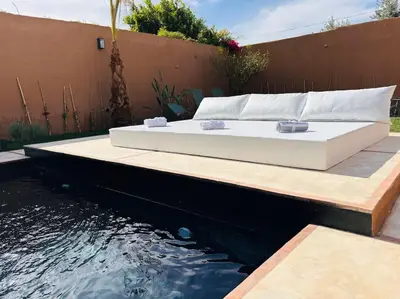 a bed sitting on a wooden platform next to a body of water at Loft Marrakech 5 min du centre super emplacement in Marrakech
