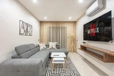 a living room with a gray couch and a tv at RA 14 Calme et Cosy Netflix, Wifi et parking gratuits in Marrakech