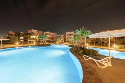a swimming pool at night with a chair and an umbrella at Relax Front Of Golf-Atlas in Marrakech