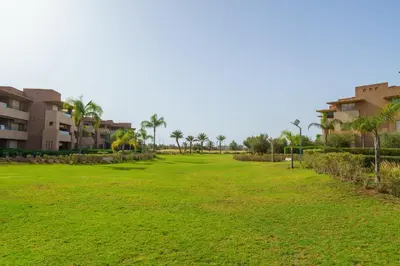 a large green field with palm trees and buildings at Chic Escape Sunny Terrace Pool Cenima Bed Fiber Wi-Fi in Marrakech