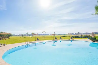 a large swimming pool with chairs and a field at Chic Escape Sunny Terrace Pool Cenima Bed Fiber Wi-Fi in Marrakech