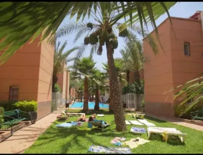 a group of people laying on the grass under palm trees at Riad marrakech boujloud in Marrakech