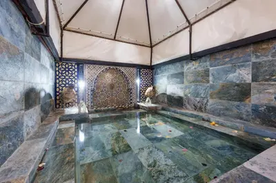 a swimming pool in a room with a stone wall at Riad Khadoj-Marrakech-Traditional in Marrakech