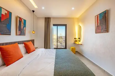 a bedroom with a bed with orange pillows and a window at R35 Paisible et tout confort : Netflix+parking+Wifi gratuit in Marrakech