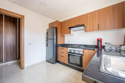 a kitchen with a stainless steel refrigerator and wooden cabinets at appartement 3 chambres avec piscine in Marrakech