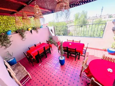a patio with red tables and chairs on a balcony at Al Bahja family in Marrakech