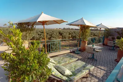 a patio with umbrellas and a table and chairs at Riad VUE D'AGDAL in Marrakech
