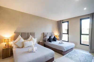 a hotel room with two beds and two windows at Villa Hicham Golf Marrakech in Marrakech