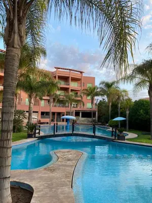 a swimming pool with a palm tree and a building at Cosy Appartement Avec Piscine in Marrakech