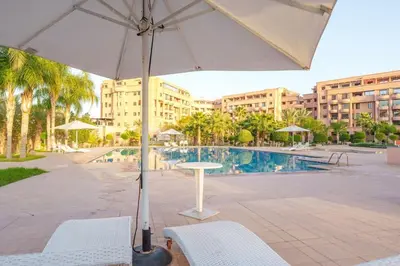 a table and chairs with an umbrella next to a pool at Luxury Place M Avenue in Marrakech