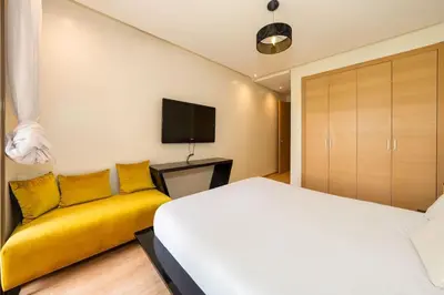 a bedroom with a bed and a yellow couch at Relax Front Of Pool-Golf-Atlas in Marrakech