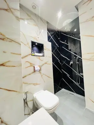 a bathroom with a toilet and a tv on the wall at Les palmiers de marrakesh in Donar Zratna
