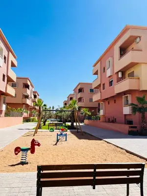 a park with a bench and swings in front of a building at Les palmiers de marrakesh in Donar Zratna