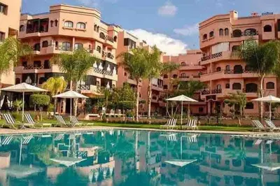 a swimming pool in front of a large building at Appart Premium Village Marrakech in Marrakech
